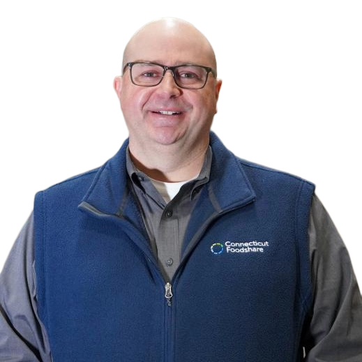 A headshot of Jason Jakubowski, president and CEO of Connecticut Foodshare. He is wearing glasses and a navy blue vest with the logo on it.